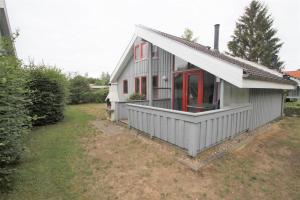 ein kleines weißes Haus mit roten Fenstern auf einem Hof in der Unterkunft Wildgans 271 in Mirow