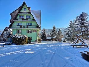 a building with a snow covered yard in front of it at Dunajecki Zakątek z Jacuzzi in Biały Dunajec