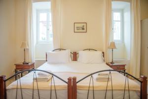 a bedroom with a bed with two tables and two windows at Archontiko Eleni Hotel in Andros