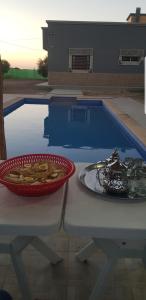 un bol de nourriture sur une table à côté d'une piscine dans l'établissement Havre de paix, à Taourirt