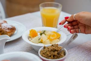 a person eating a bowl of food with a glass of orange juice at Archontiko Eleni Hotel in Andros