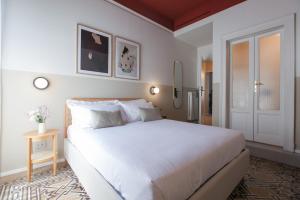une chambre avec un grand lit blanc et une fenêtre dans l'établissement Cà Bèla - Certosa SUITES, à Milan