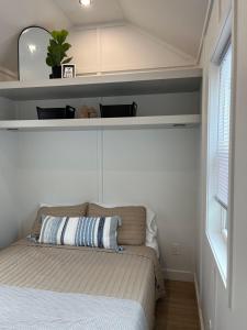 a bedroom with a bed with a shelf above it at The Sam Tiny Home in Perry