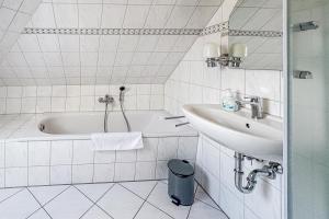 a white bathroom with a tub and a sink at Villa Viktoria Whg 20 - "Ostseeloft" in Kölpinsee +8 photos