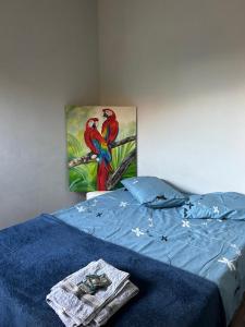 カンポ・グランデにあるHouse Dora AP 2 C AR CONDICIONADOのベッドの上に座っている2羽のオウムの絵