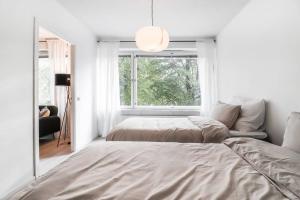 een witte slaapkamer met twee bedden en een raam bij Cosy flat with good transport connections and Free parking in Vantaa