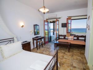 a bedroom with a bed and a living room with the ocean at Niriides Studios & Apartments in Kithnos