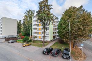 een parkeerplaats met auto's geparkeerd voor een gebouw bij Cosy flat with good transport connections and Free parking in Vantaa