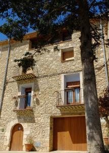 - un bâtiment en pierre avec deux portes et un arbre dans l'établissement Abadia de Cal Bessó, à Alberola