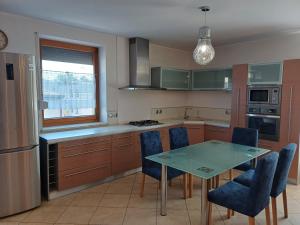 a kitchen with a glass table and blue chairs at Apartamenty Aneta in Pleszew