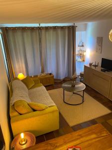 a living room with a yellow couch and a table at Studio terrasse plein sud avec coin montagne in Saint-Chaffrey