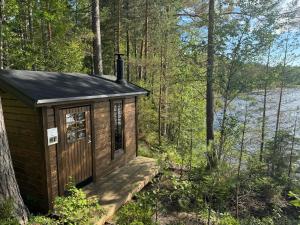 a cabin in the woods with a view of the water at Tranan glamping in Svanhult +9 photos