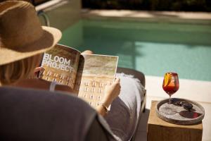 a woman in a hat reading a book and a glass of wine at Azur Hotel in Athens