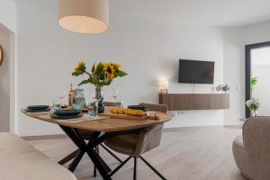 a dining room table with a vase of flowers on it at Casa Los Vecinos - Luxury Rooftop Penthouse in Estepona