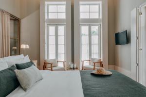 a bedroom with a white bed and two windows at Casa das Lérias in Amarante +49 photos
