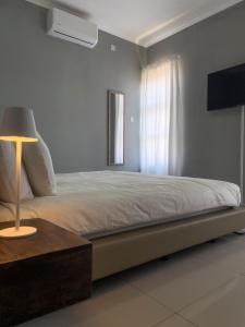 ein Schlafzimmer mit einem Bett mit einem Tisch und einer Lampe in der Unterkunft Grey Net in Palatswe