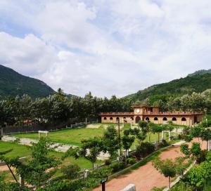 NandigundaSatya Anantham Eco Retreat - Mystic Hotels的田野中的一栋建筑，背景是群山