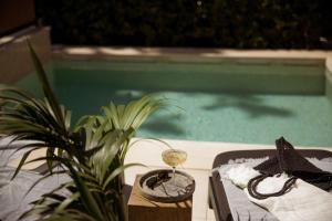 a table with a glass of wine next to a swimming pool at Azur Hotel in Athens