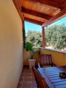 a porch with a wooden table and chairs and a potted plant at Tina in Kolan +4 photos