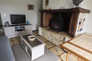 a living room with a fireplace and a tv at Ferme rénovée tout confort en pleine campagne in Larbey