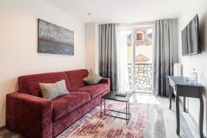 a living room with a red couch and a table at Sole Boutique Hotel in Vipiteno