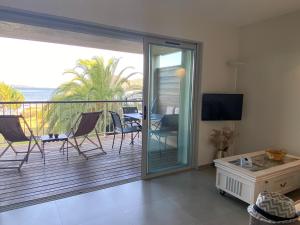 a living room with a balcony with a table and chairs at Les oliviers 6 - Appartement pieds dans l'eau in Porto-Vecchio