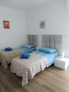 2 Betten in einem Schlafzimmer mit blauen Handtüchern darauf in der Unterkunft Da Nonna Maria in Grottaglie