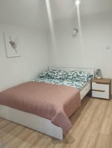 a bedroom with a bed and a wooden floor at DOMEK POD SOSNAMI in Krasnobród