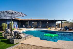 a pool with chairs and an umbrella next to a house at Basketball Court Heated Pool Mini Golf & More in Glendale