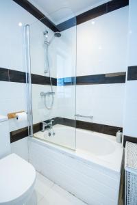 a bathroom with a shower and a tub and a toilet at Swn y Mor in Rhosneigr