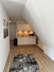 an attic kitchen with white cabinets and wooden floors at FeWo Foorden Wohnglück 1 in Hesel