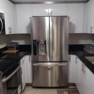 Un refrigerador de acero inoxidable en una cocina con gabinetes blancos. en Cozy home Southside Jax, en Jacksonville