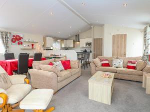 a living room with two couches and a kitchen at 21 Norman Drive Lodge in Great Yarmouth
