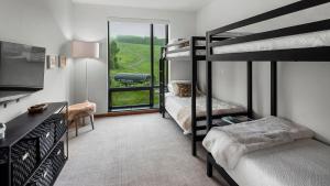 a bedroom with two bunk beds and a tv at 4F One Spruce Peak Stowe Mountain Resort Ski in Ski Out 4 bed Sleeps 10 in Stowe