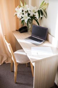 a laptop computer sitting on a desk with a vase of flowers at Hotel SPA Arkadia in Apšuciems