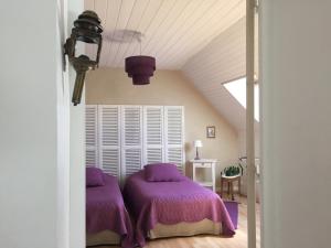 - une chambre avec des couettes violettes sur un lit dans l'établissement Gite Les Volets Rouges, à Vigny