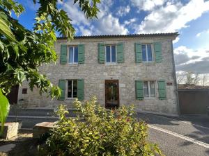 una vecchia casa in pietra con persiane verdi di Bastide Bellevue a Gaudonville
