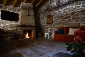 a living room with a fireplace and a couch at Casa do Bó Nel in Valpaços