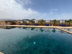 een groot waterbassin met blauwe stoelen en bomen bij Jnane Ayam Atlas in Ourika +58 foto's