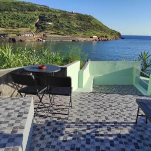 a patio with a table and chairs next to the water at Mar Rosa - Terraço Vista Praia in Horta