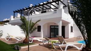 a white house with chairs and a swimming pool at Villa Real Oliva in Corralejo