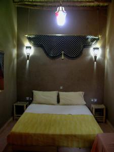 a bedroom with a bed with two lights on the wall at Le Drom'blanc in Mhamid