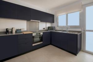 a kitchen with black cabinets and a large window at Amazing Two Bedroom Apartment in Larnaca