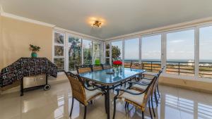 a dining room with a table and chairs and the ocean at 10 Malibu, Beverly Hills Estate in Ballito