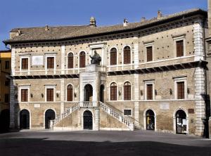 a large brick building with a statue in front of it at Il Punto Fermo in Fermo