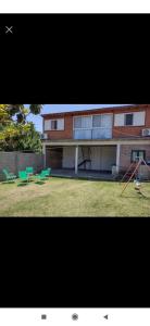 a building with a yard with green chairs and a house at Depto mina clavero Córdoba zona residencial in Mina Clavero