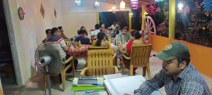 a group of people sitting at tables in a restaurant at Bhitarkanika Eco Resort TENT in Righāgarh