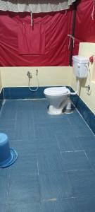 a bathroom with a toilet and a red wall at Bhitarkanika Eco Resort TENT in Righāgarh