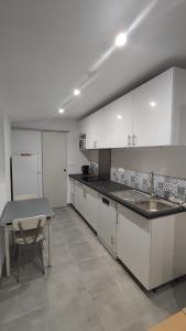 a kitchen with white cabinets and a table and a sink at Studio Proche Plage du Prophète in Marseille