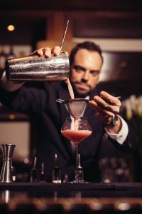 a man pouring a drink into a martini glass at InterContinental Genève by IHG in Geneva